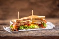 Club sandwich on a rustic table witch chicken, bacon and veg