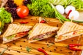 Club sandwiches with different fillings on wooden cutting board