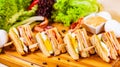 Club sandwiches with egg, ham, bacon, vegetables on wooden cutting board Royalty Free Stock Photo