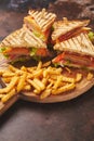 Club sandwiches served on a wooden board. With hot French fries Royalty Free Stock Photo