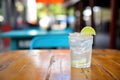 a club soda with lime slice on the rim, outdoor cafe table
