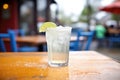 a club soda with lime slice on the rim, outdoor cafe table