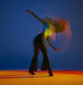 Clubbing. Portrait of young girl dancing heels dance in stylish clothes over blue background in neon with mixed lights Royalty Free Stock Photo