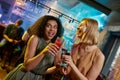 Clubbing time. Attractive young women looking playful, posing with cocktail in their hands. Friends celebrating, having Royalty Free Stock Photo