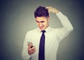 Clueless confused business man having troubles with his smartphone. Royalty Free Stock Photo