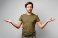 Clueless young man gesturing i don't know against grey background Royalty Free Stock Photo