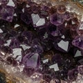 Cluster of amethyst crystals displaying deep purple hues with a hexagonal structure.