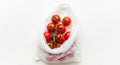 Bunch of Cherry Tomatoes in a White Plastic Shopping Bag on White Background vine fresh Royalty Free Stock Photo