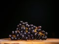 Cluster of dark grapes on wooden board and dark background. Fresh fruit product. Tasty desert. Still life