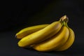 Cluster Of Five Vibrant Yellow Bananas With Tiny Black Speckles, On Dark Surface With Soft Shadow