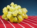 Cluster of fresh juicy grapes on red and white stripe classic country table cloth. Blue gradient background. Copy space Royalty Free Stock Photo