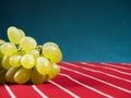 Cluster of fresh juicy grapes on red and white stripe classic country table cloth. Blue gradient background. Copy space Royalty Free Stock Photo