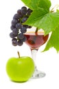 The cluster of grapes and apple lie near a wine glass with brand Royalty Free Stock Photo