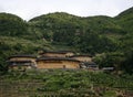 A cluster of Hakka Tulou homes in the valley backed by the mountain range