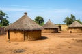 A cluster of huts is situated on top of a dirt field, A traditional African mud hut village, AI Generated Royalty Free Stock Photo