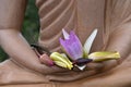 A cluster of lotus flowers rests on the hand of a marble Buddha in a sitting position. Royalty Free Stock Photo