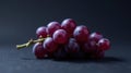 A cluster of ripe red grapes on a dark surface, subtly illuminated, showcasing the exquisite texture and color of the fruit. Royalty Free Stock Photo