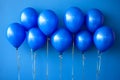 Cluster of shiny blue balloons tied with metallic strings creating a festive playful atmosphere in a minimalist setting for par