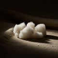A cluster of white cotton balls sits on a textured beige fabric surface, illuminated by a Royalty Free Stock Photo