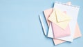 Cluttered office desk. Flat lay, top view heap of pink notebook, notepad, document, envelope on blue background