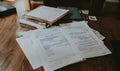 a close-up shot of scattered documents and a clipboard on a wooden desk, creating a sense of busy work and paperwork overload Royalty Free Stock Photo
