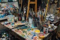A cluttered work desk with scattered paint brushes and tubes of paint AI generated Royalty Free Stock Photo