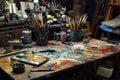 A cluttered work desk with scattered paint brushes and tubes of paint AI generated Royalty Free Stock Photo