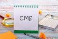 CMS (Content Management System) acronym in an upright notebook in a composition with office supplies Royalty Free Stock Photo