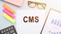 CMS Content Management System with text on notepad and office accessories on white desk Royalty Free Stock Photo