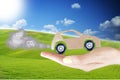 CO2 pollution concept with cardboard model car with exhaust smoke clouds in woman hand, natural background with green grass and