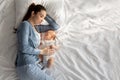 Co-sleeping with baby. Young woman napping in bed with her newborn child