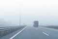 Coach bus on almost empty blue foggy misty rainy highway intercity road with low poor visibility on cold spring autumn