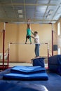 Coach Helping Girl Gymnast with Handstand on Uneven Bars