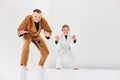 Coach, professional judo, jiu-jitsu trainer in uniform posing with little boy, child in white kimono. Training activity Royalty Free Stock Photo