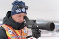 Coach of Russian biathlon team watches biathletes in monocle at shooting range of biathlon stadium. Regional Junior