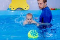 Coach teaches the baby to swim in the pool. baby splash in the water in the pool. The concept of a healthy Royalty Free Stock Photo