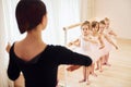 Coach teaches children. Little ballerinas preparing for performance by practicing dance moves