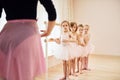 Coach teaches children. Little ballerinas preparing for performance by practicing dance moves