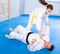 Coach teaches young woman techniques for wrestling and throwing on sports mats during judo training