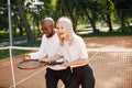 Black man teaching young woman to play tennis Royalty Free Stock Photo