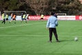 A coach watches as a team of young athletes football players trains at the stadium