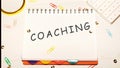 COACHING word on a checkered notebook on a light table next to a magnifying glass, paper clips, stationery buttons, a calculator Royalty Free Stock Photo