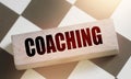 Coaching word on a wooden block put on chess board. Mentorship consulting personal achievements in career and business Royalty Free Stock Photo
