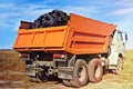 Coal in the back of the orange truck. Coal mining. Coal delivery