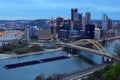 A coal barge plies the Alleghany River, passing the skyline of Pittsburgh
