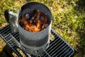 Coal of charcoal grill burning in flames with fire and lighter in barbecue chimney for BBQ evening