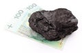 Coal lump with money on white background
