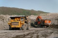 Coal mining. A BelAZ dump truck stands in front of a Hitachi excavator. The action takes