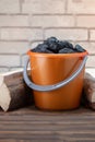 Coal pieces in the bucket and and firewood on wooden floor. Royalty Free Stock Photo