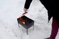 Man`s hands making campfire in mangal in forest in winter. The fire and flame in the grill, prepare to heat the barbecue. Snowdrif Royalty Free Stock Photo